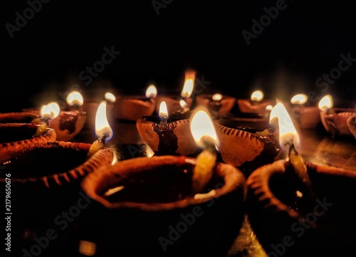 Fotografie A close-up shot of multiple traditional earthen oil lamps, known as Diya, beautifully illuminated and arranged on a metallic tray in the dark