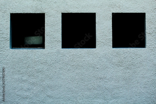 Minimalist Textured Stucco Wall with Three Black Square Openings