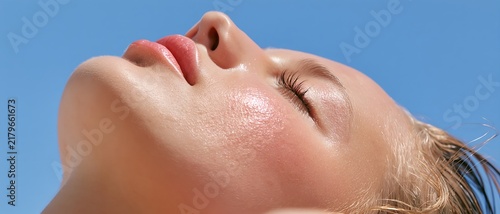 Young woman enjoying warm sunlight with eyes closed and head tilted back