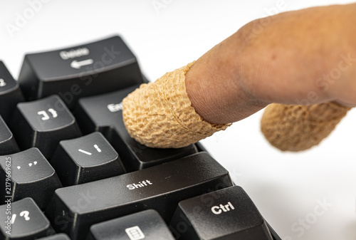 Macro shot of an injured finger covered with a bandage pressing down on a black computer keyboard shift key, symbolizing the hidden risks, dangers and consequences of a single click