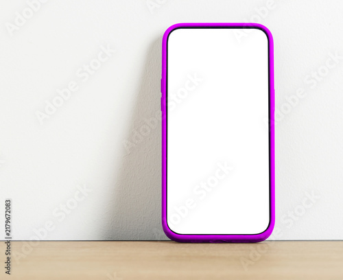 Obraz na plátně Green screen smartphone mockup leaning against a white wall on a wooden shelf