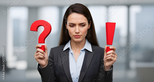Doubt and confidence. A businesswoman holds a question mark and an exclamation mark.