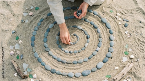 Top View Person Creating Spiral Stone Mandala in Sand on Beach