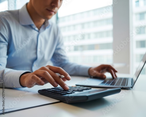 A Professional Businessman Calculating Financial Data Using A Modern Calculator And Laptop