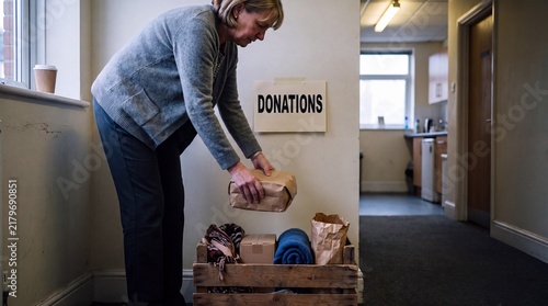 Woman donating a wrapped parcel to an office donation box