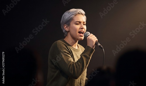 Young Female Singer Performing with Microphone on Stage Under Spotlight
