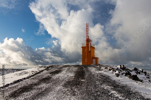 Orange lighthouse on a stony coast in Iceland. Winter landscape