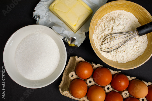 Quadro su tela Baking ingredients including brown eggs, flour, sugar, and butter arranged with