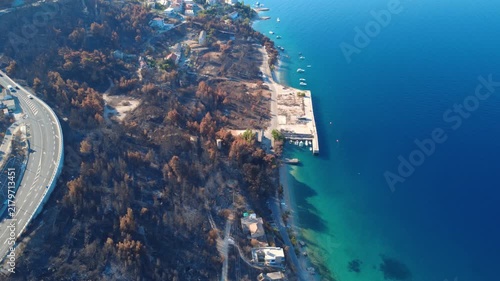 Aerial footage of a burned coastal area in Croatia beside a marina and clear blue sea.