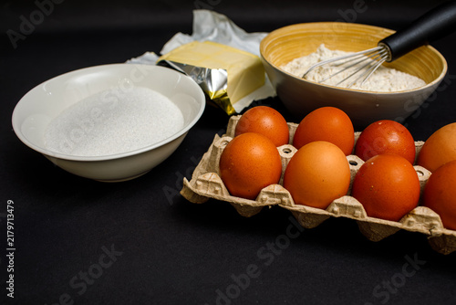 Quadro su tela Baking ingredients including brown eggs, flour, sugar, and butter arranged with