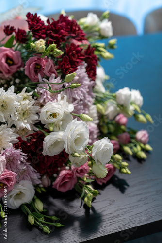 Elegant flower bouquet of white eustoma and burgundy chrysanthemums on dark wooden table