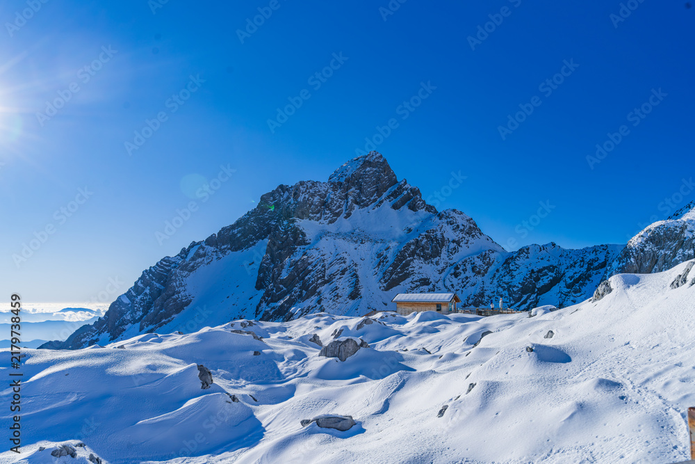 Fototapeta premium Snow-capped peak towering above a remote mountain cabin, Yulong Snow Mountain, Lijiang