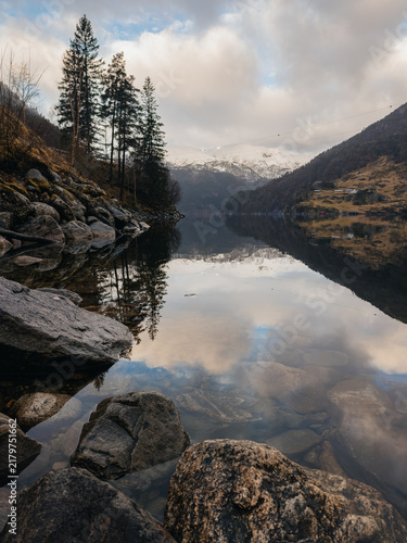 Tranquil Norwegian fjord with snowy mountains and perfect water reflection
