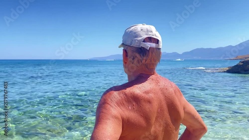 Active senior mature man meditating on sea beach,breathing fresh air on ocean coast.Outdoor nature,freedom and traveling concept