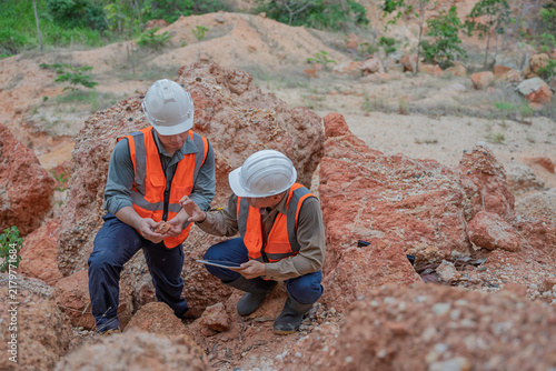 Fotografía Two male geologists inspect rock and soil samples while reviewing field data on a tablet at an excavation site