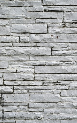 Фотография White painted machine-cut sawn stone masonry surface in a vertical close-up comp