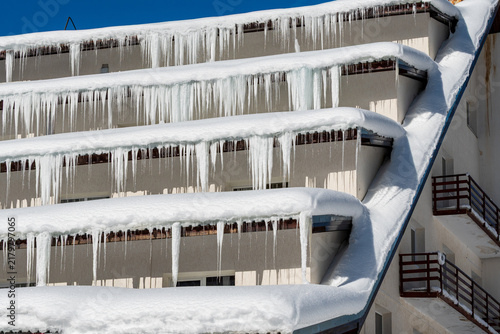 Obraz na plátne Thick icicles and deep snow cover balconies of a mountain hotel in Balea during bright winter weather