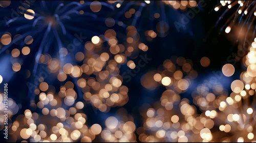 Exploding fireworks with golden bursts and warm golden bokeh lights glowing against a deep dark blue backdrop, joyful New Year and Christmas holiday video for celebrations.