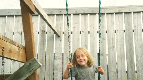 Close-up of a boy smiling while swinging in warm golden light