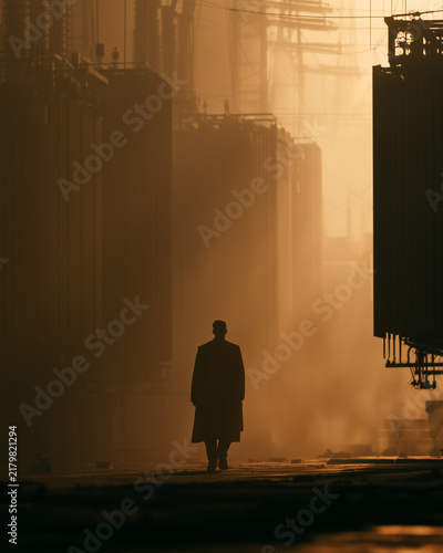 Lone Electrical Technician Walking Between Massive Industrial Transformers