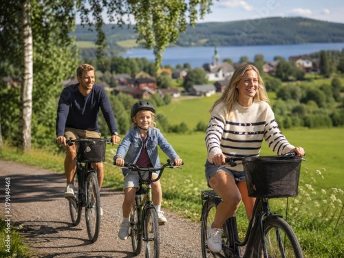 Familie mit Kind auf Fahrradtour durch die schwedische Seenlandschaft. Freundliches Sommermotiv für aktiven Urlaub, Naturerlebnis, lokalen Tourismus und Reisekatalog.