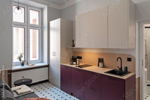 Modern kitchen interior with kitchen furniture and counter and kitchen sink. Studio apartment with living room with window. Nobody.