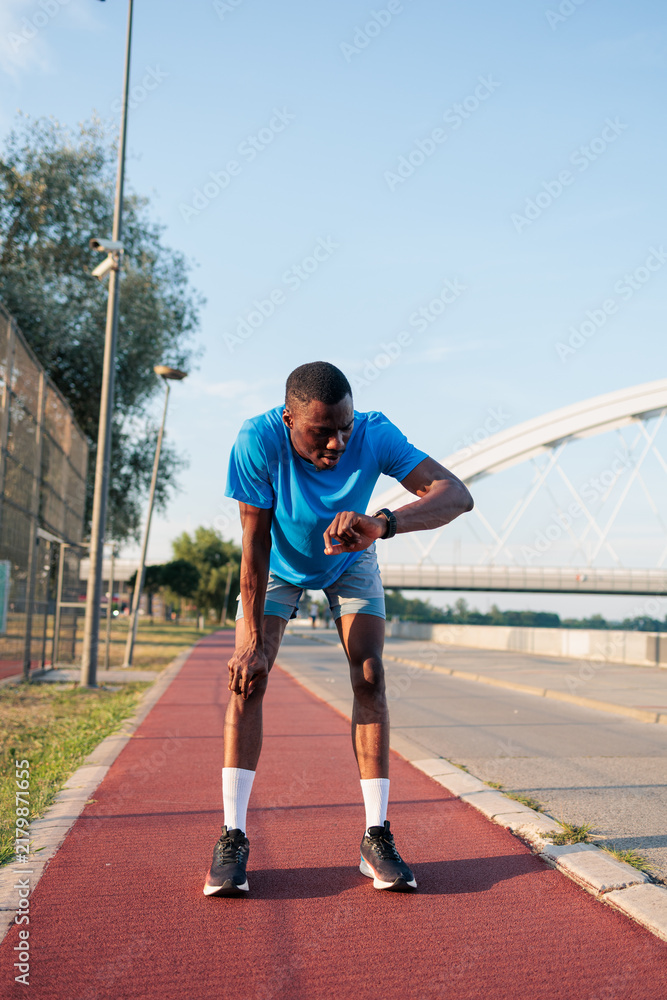 Obraz premium Male athlete recovering from a run checking smartwatch data