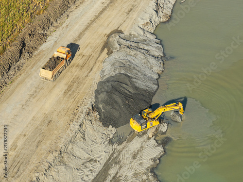 Aerial view of a heavy excavator digging gravel from water beside a dump truck during infrastructure construction at Autostrada A7 road junction in Bacau. Moldova Highway in Romania