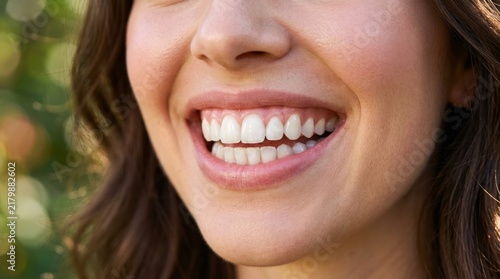 A close up shows a smiling woman with bright white teeth.