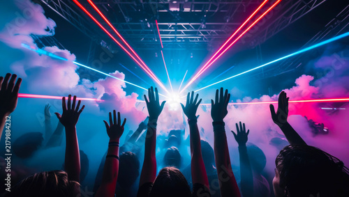 Cheering crowd at a live music festival under dynamic laser lights and clouds of stage smoke. Energetic party nightlife event.
