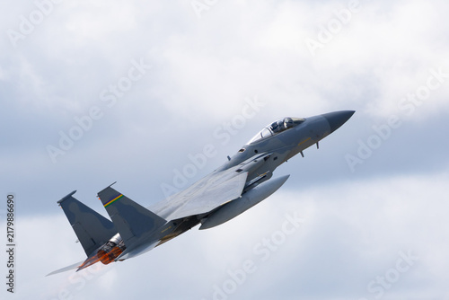 Fotografie Side view of a F-15 Eagle climbing  with afterburners on, against clouds