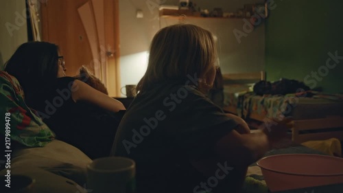 Mother and son enjoy a cozy evening indoors while sharing snacks and watching television. The footage represents family life, togetherness, leisure, happiness, and a warm domestic atmosphere.
