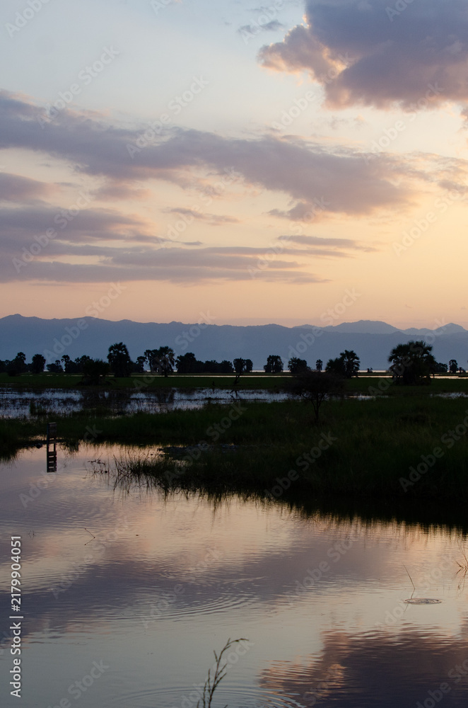 Obraz premium Serene African sunset landscape reflection on calm lake water with distant mountains