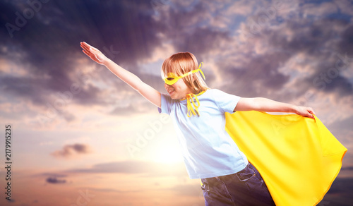 Cuadro en lienzo Little boy with yellow superhero cape and mask against sunset sky