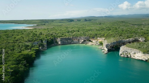 Aerial view of a turquoise bay nestled between lush cliffs and dense, green vegetation