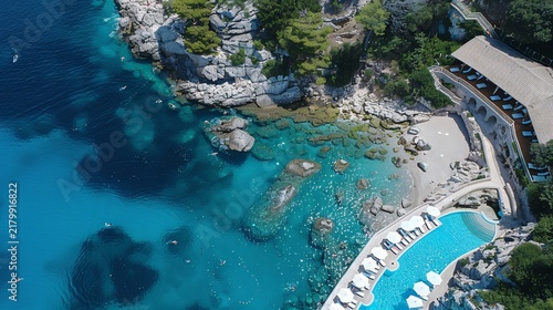 Aerial view of cove with turquoise water, a pool, a beach, and a restaurant