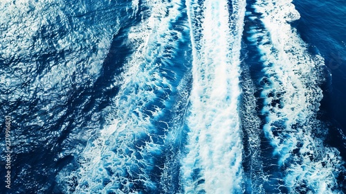 Aerial view of foamy boat wake trailing across a dark blue ocean surface