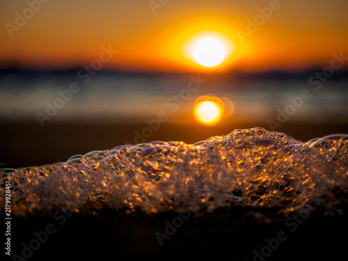 Фотография Golden sunset over the ocean with foamy waves and bokeh effect