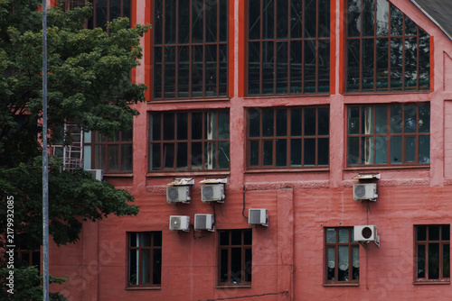 White AC units on pink building facade with large windows. High quality photo