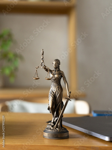 Bronze Lady Justice statue on wooden desk in office. legal advice, lawyer online.