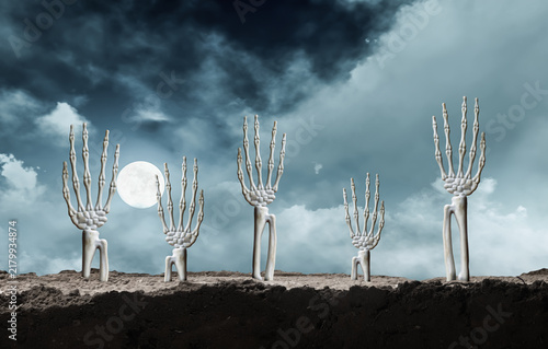 Konstfotografi Skeleton hands emerging from dark dirt reaching up toward a spooky night sky wit