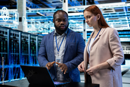 Cuadro en lienzo Engineering team coordinates data center backups on a laptop, reviewing recovery protocols and upgrading equipment components together in a server farm