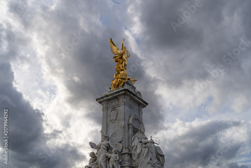 Fotografie Golden Victory Statue on Monument Against Dramatic Cloudy Sky