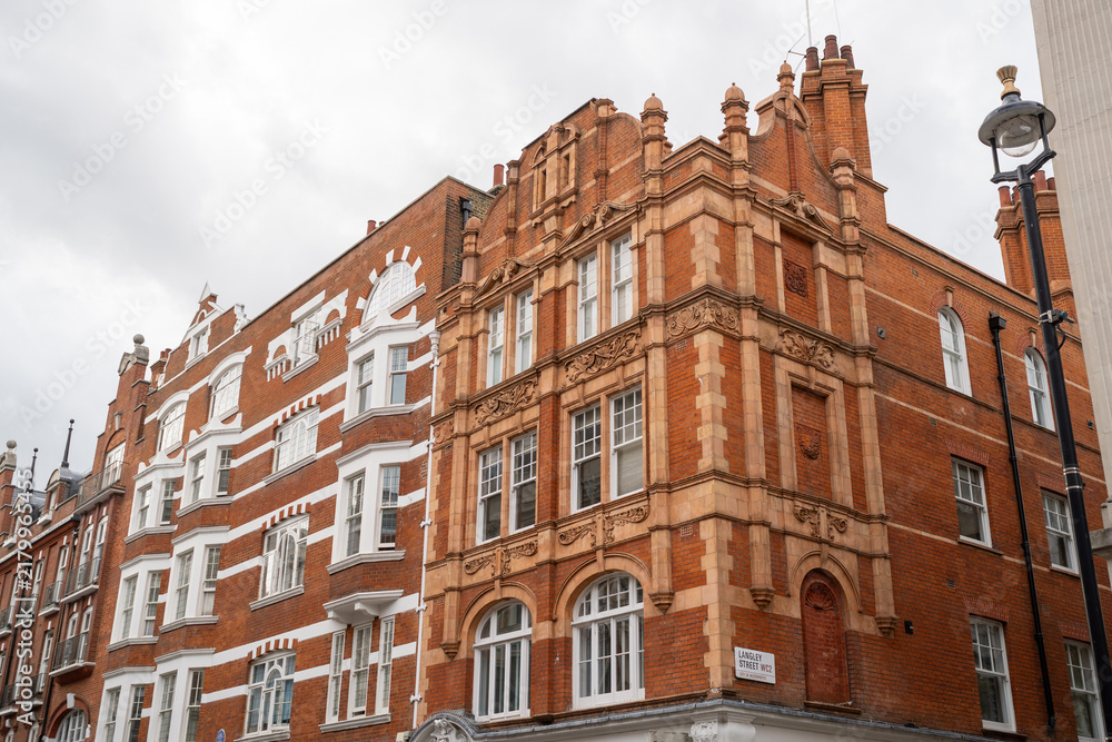 Obraz premium Historic Red Brick Building With Ornate Architecture Under Cloudy Sky