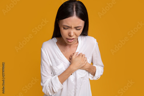 Foto Woman holding chest while experiencing sudden discomfort