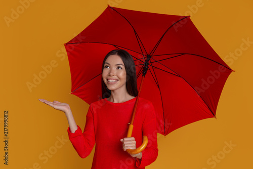 Happy woman enjoying imagined rain under red umbrella