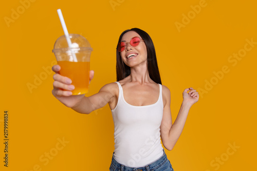 Happy woman offering refreshing cold drink to camera