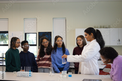 Cuadro en lienzo Female teacher demonstrating with Erlenmeyer flask to teenage students in lab, w