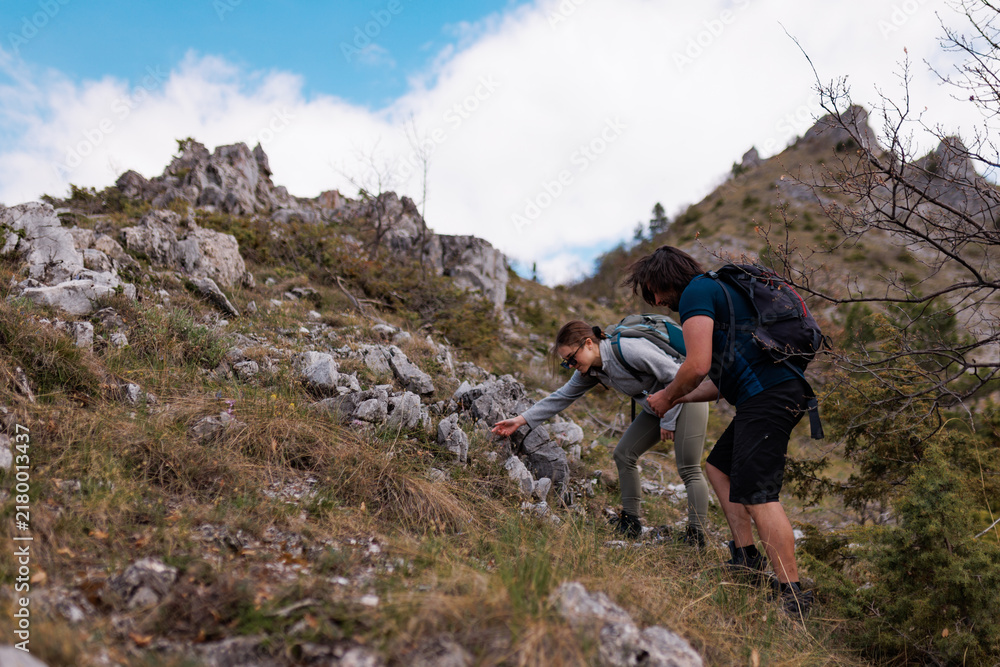 Fototapeta premium Group of friends hiking together on a rocky mountain trail with backpacks, exploring alpine slopes and enjoying an outdoor adventure