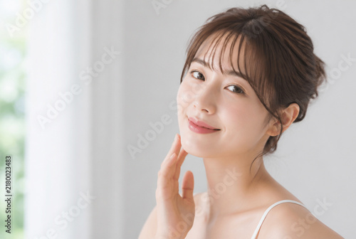 Obraz na płótnie 笑顔で頬に手を当てる美容イメージの若い日本人女性